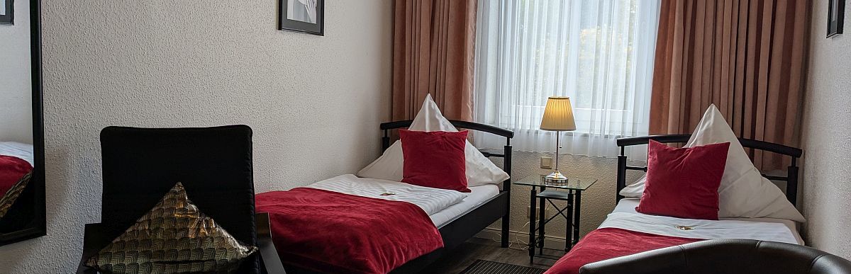 Innenaufnahme eines Doppelzimmers im Hotel Jägerhof in Mayen. Das Zimmer verfügt über zwei getrennte Betten. Im Zimmer befindet sich ein eigenes Bad mit Dusche und Kosmetikspiegel. Das Zimmer wird täglich gereinigt.